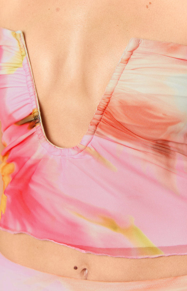 Close-up of the ruched deep V-neckline and raw-cut hem of a pink floral mesh crop top