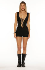 Black ribbed playsuit featuring a deep lace-up V-neckline and lace-up side panels