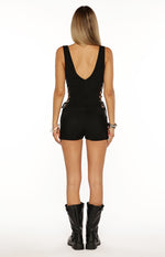 Rear view of a black playsuit with a deep V-neck back and lace-up details on the sides