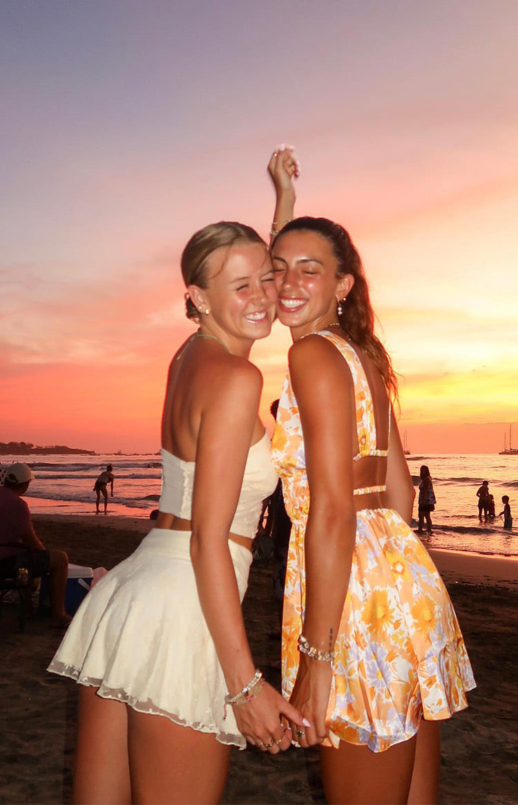 Rear view of an orange floral mini dress with a low open back and thin horizontal strap details