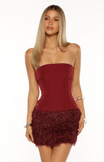 Front view of a burgundy strapless mini dress with a smooth fitted bodice and a textured fur skirt