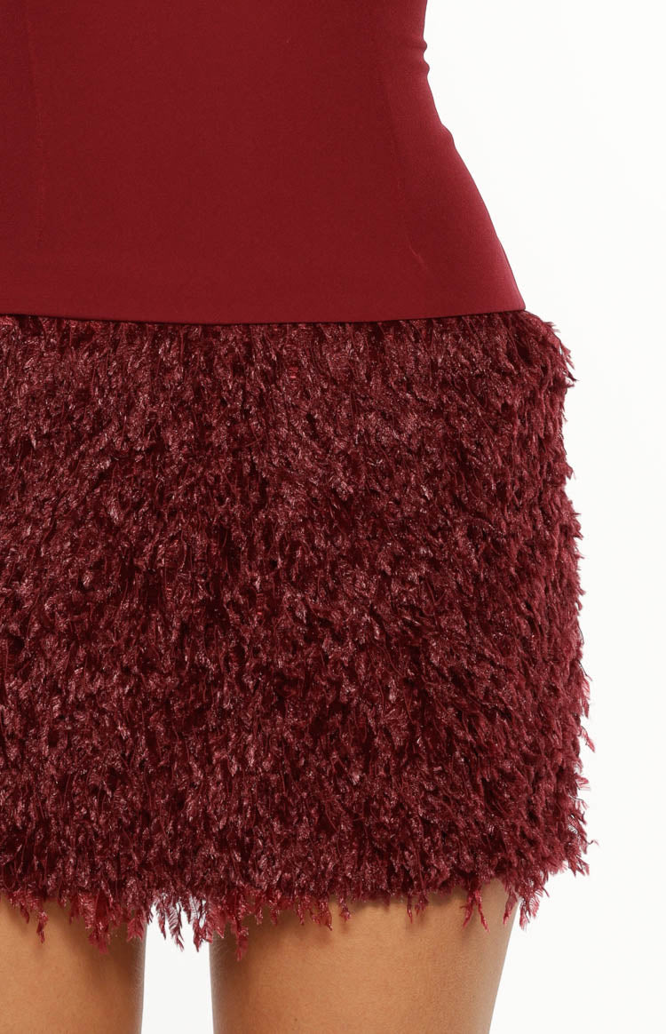 Close-up of the burgundy fur texture on the mini dress skirt, with a smooth burgundy waistline