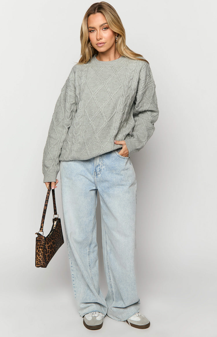 Front view of a grey cable knit sweater with a relaxed fit and prominent diamond and rope patterns