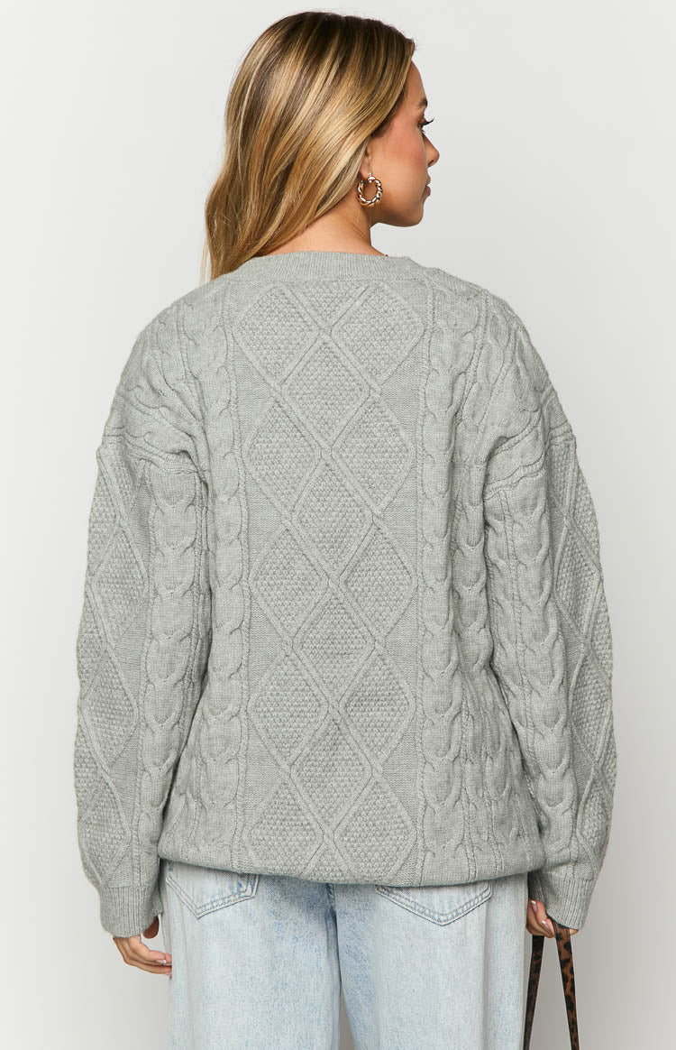 Rear view of a grey cable knit sweater showing the diamond pattern on the back and braided cables on the sleeves