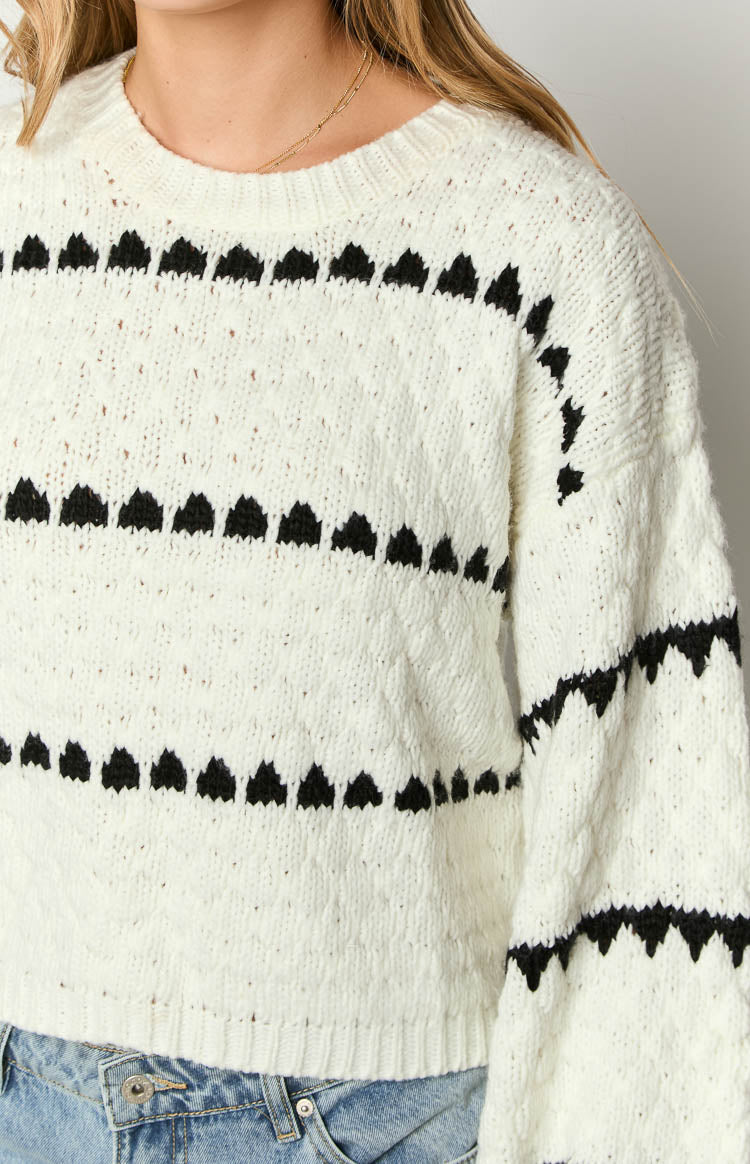 Close-up of the white knit sweater showing the black heart stripe pattern and textured knit