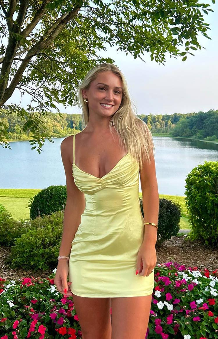 Full front view of a honey yellow satin mini dress with a ruched sweetheart neckline and thin spaghetti straps