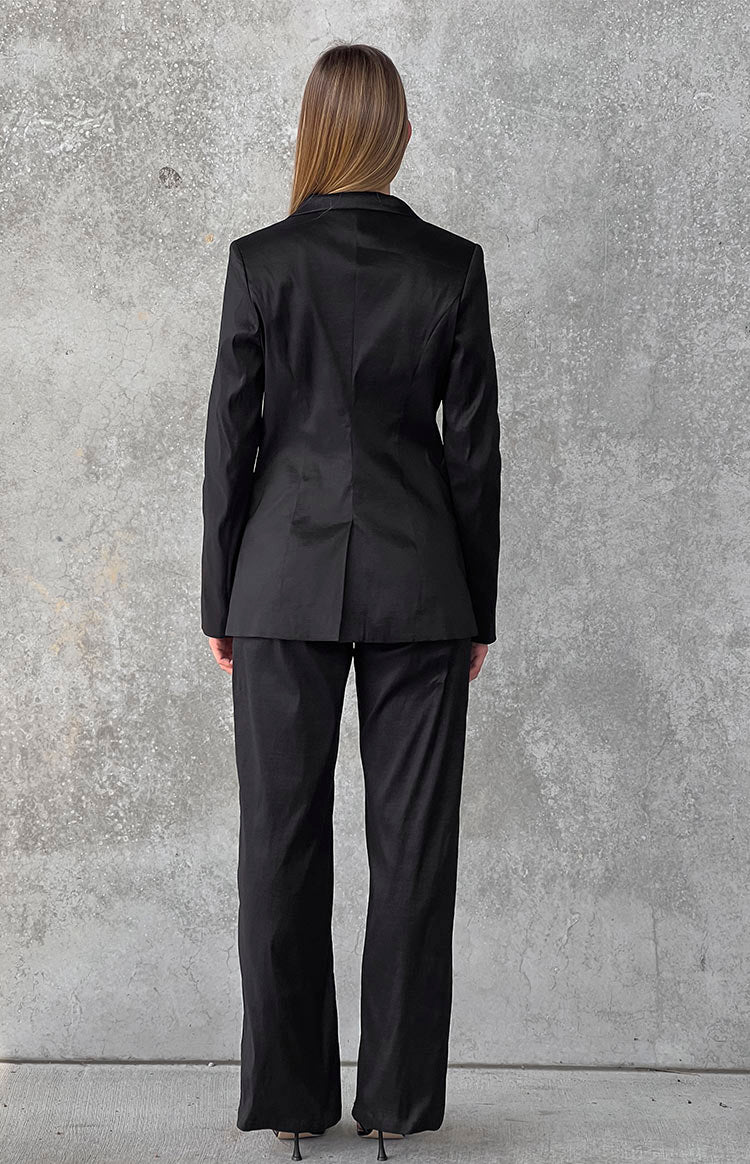 Rear view of black wide-leg pants, showing the full length and relaxed drape of the smooth fabric