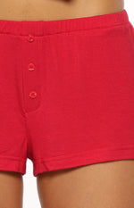 Close-up of red mini pajama shorts with three matching buttons on the front and an elasticated waistband