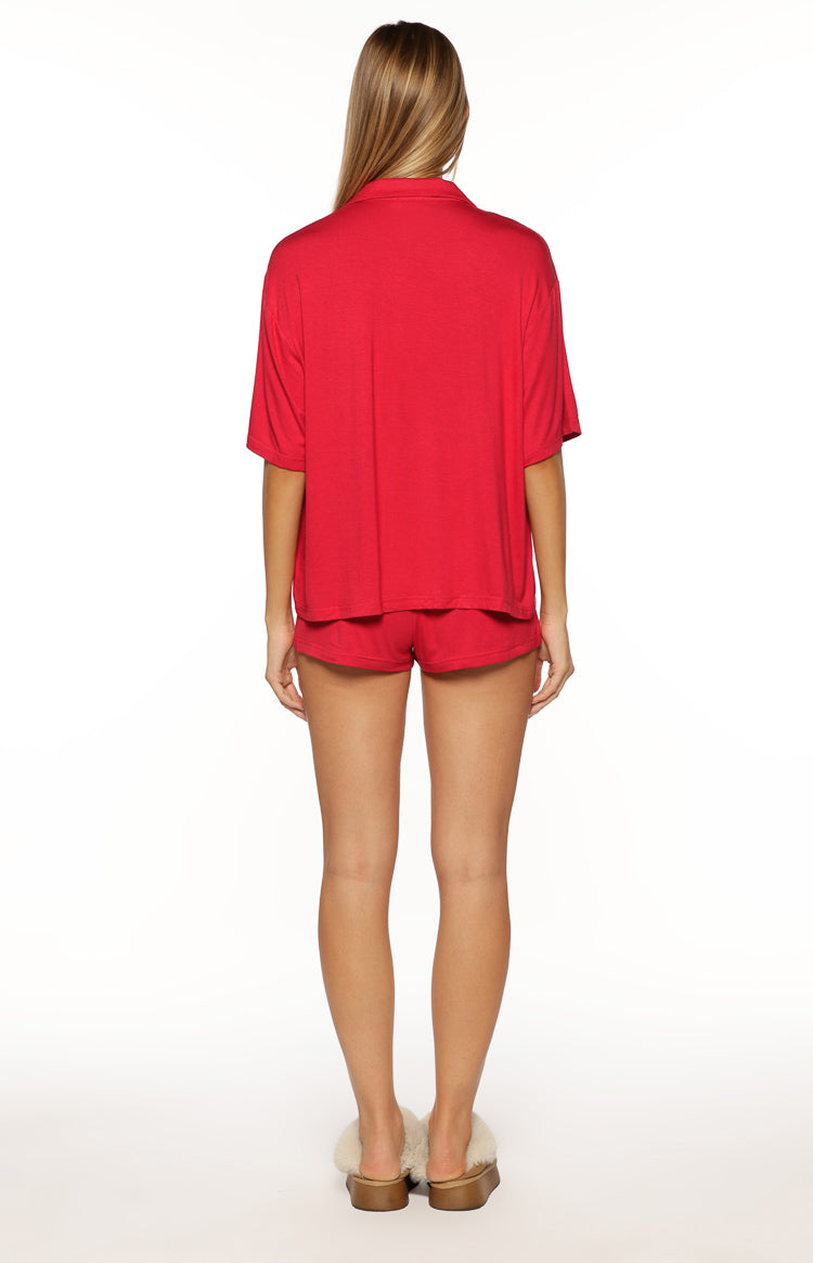 Rear view of a burgundy pajama shirt with a collared neckline and short sleeves, showing its relaxed fit