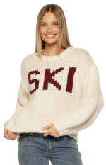 Front view of a cream chunky knit sweater with burgundy "SKI" jacquard lettering and ribbed cuffs
