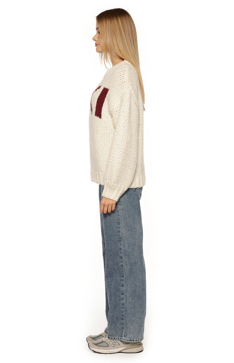 Side view of a cream chunky knit sweater with a relaxed fit and long sleeves, showing the burgundy jacquard pattern