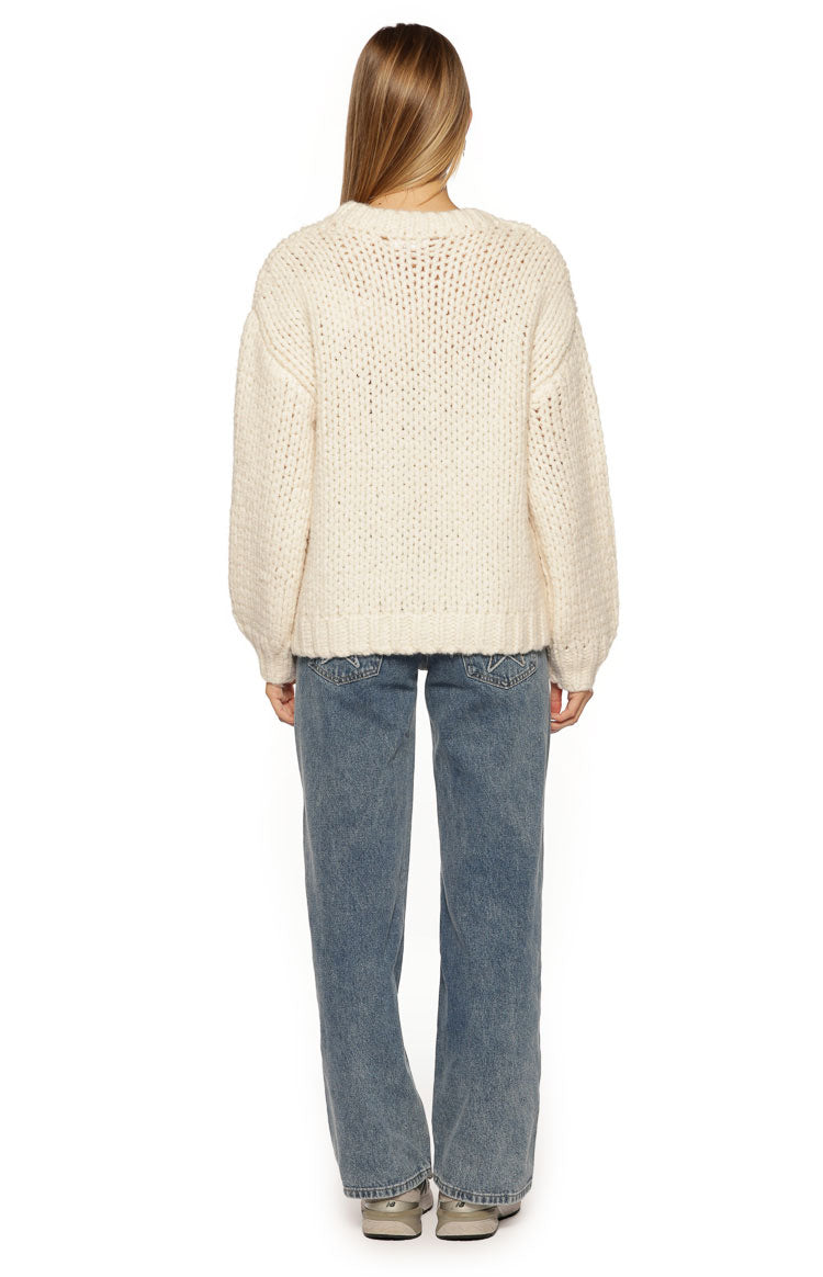 Rear view of a cream chunky knit sweater with a relaxed fit, dropped shoulders, and ribbed hem