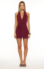Front view of a burgundy halter neck mini dress with a deep V-neckline and a self-tie waist