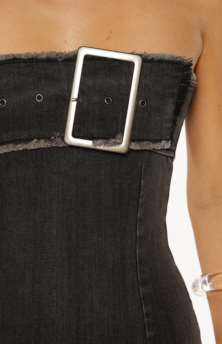 Close-up of the large silver buckle, eyelets, and frayed top edge of the black washed denim dress