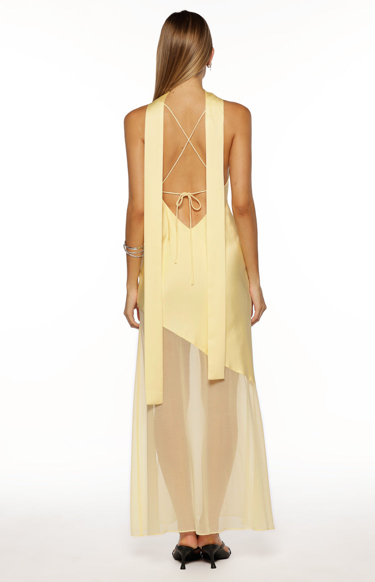 Rear view of a yellow satin maxi dress with a low scoop back, criss-cross tie straps, long scarf panels, and sheer skirt
