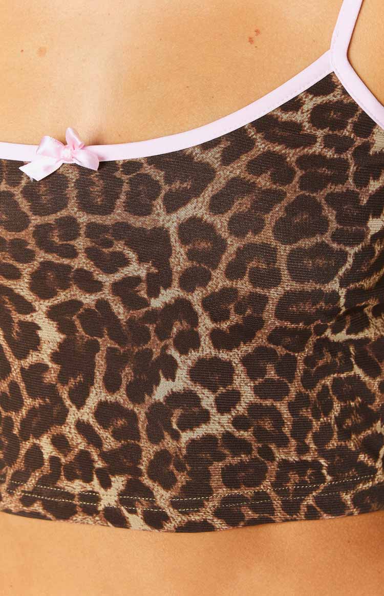 Close-up of the pink bow detail on the strap of a leopard print mesh cami crop top with pink trim