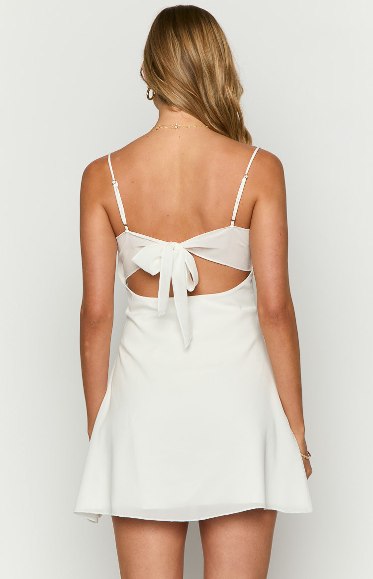 Rear view of a white mini dress with a tie-back bow, thin spaghetti straps, and side cutouts