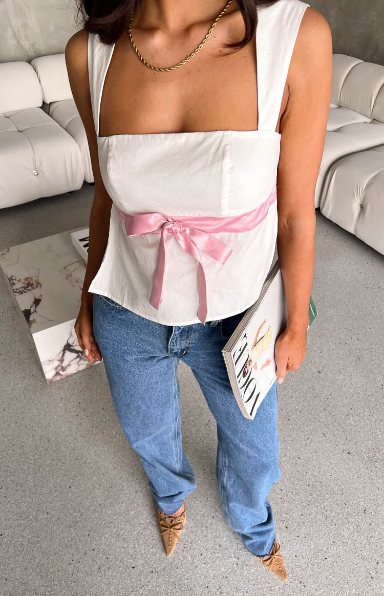 Close-up of the pink ribbon bow detail on the front of the white square neck top