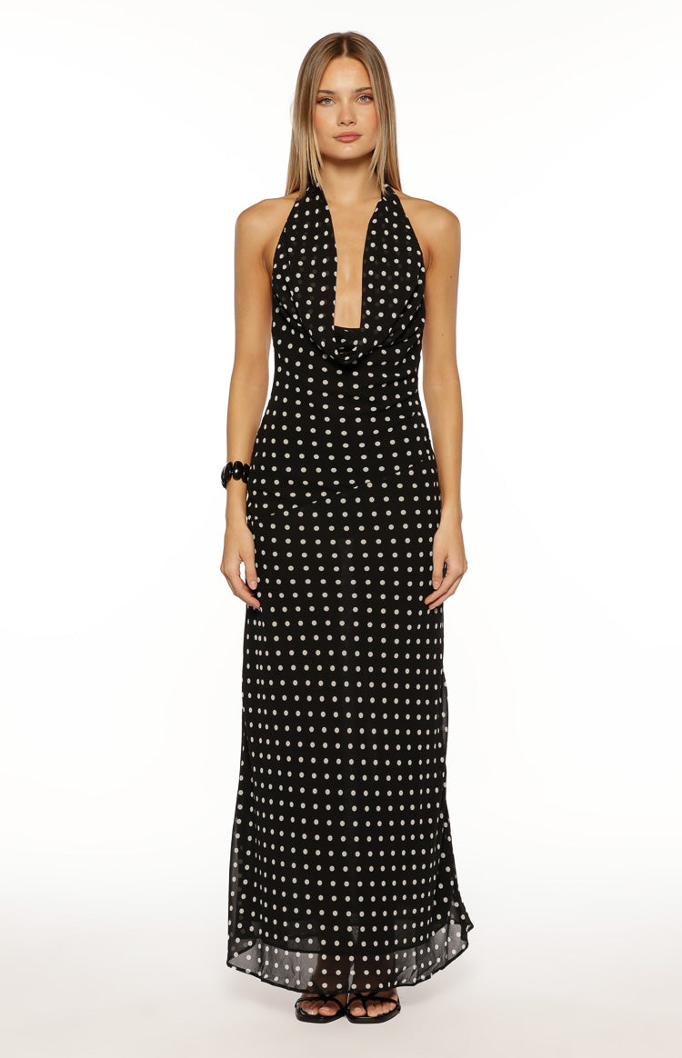 Front view of a black polka dot maxi dress, highlighting the cowl neck, halter straps, and sheer hem