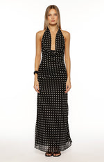 Front view of a black polka dot maxi dress, highlighting the cowl neck, halter straps, and sheer hem
