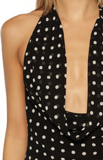 Close-up of the deep cowl neckline and halter strap on a black polka dot maxi dress