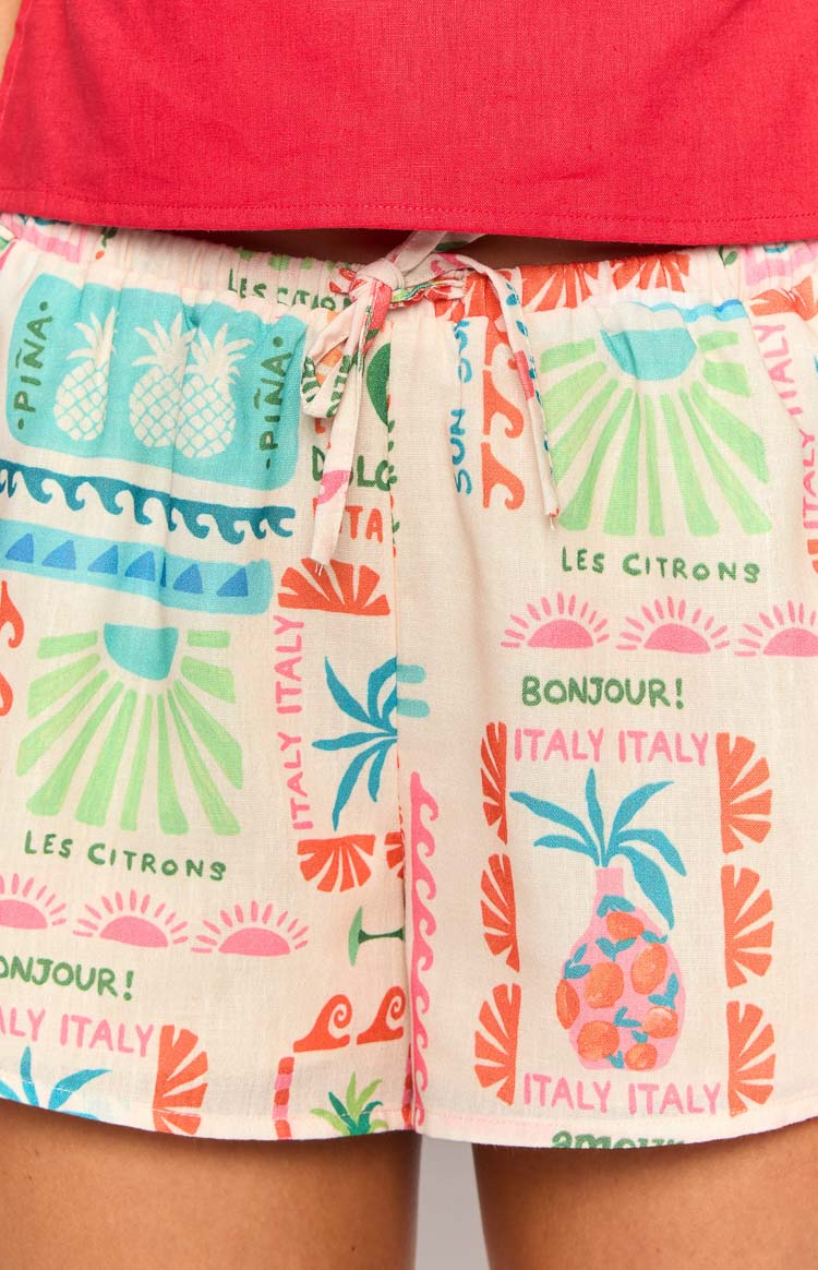 Close-up of the elasticated drawstring waist and the vibrant multi-colour fruit and text print on the off-white shorts