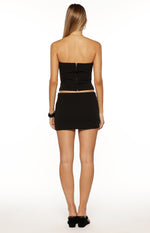 Rear view of a black low-waisted mini skirt with a fitted silhouette
