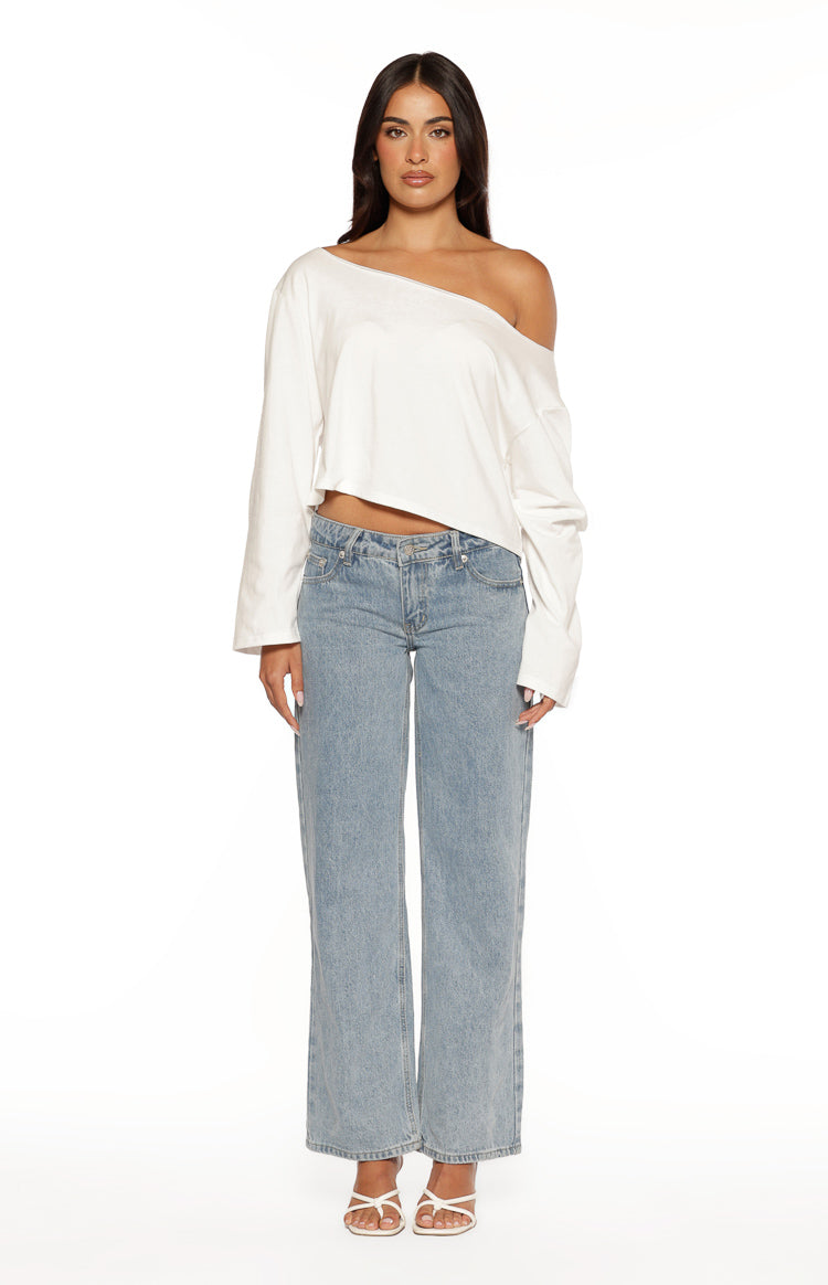 White off-shoulder long sleeve top with a wide neckline draped off one shoulder and a relaxed cropped fit