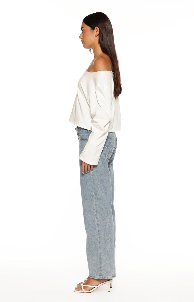 Side view of a white off-shoulder long sleeve top with a relaxed fit and cropped hem