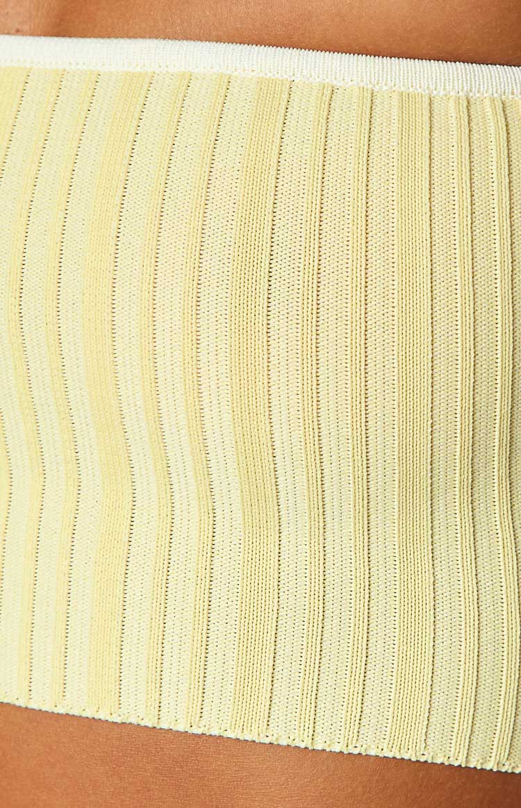 Close-up of the fine yellow ribbed knit fabric with white contrast binding at the edges
