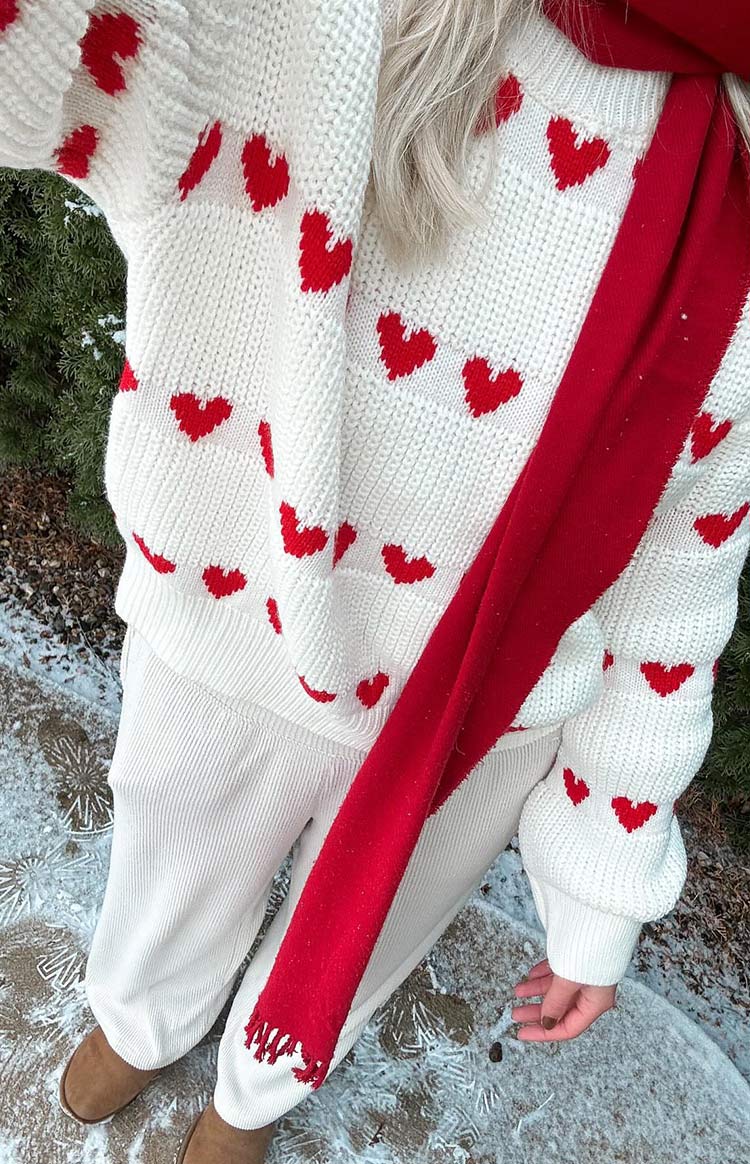 Close-up of the chunky white knit jumper with red heart pattern and ribbed sleeve cuff