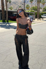 Black PU leather crop top with thin spaghetti straps and a curved neckline featuring silver eyelet lacing