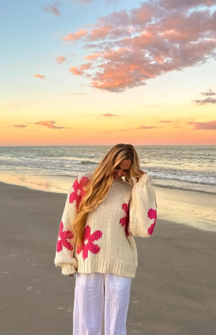 Relaxed cream knit sweater with large pink flower patterns, a round neck, and wide balloon sleeves