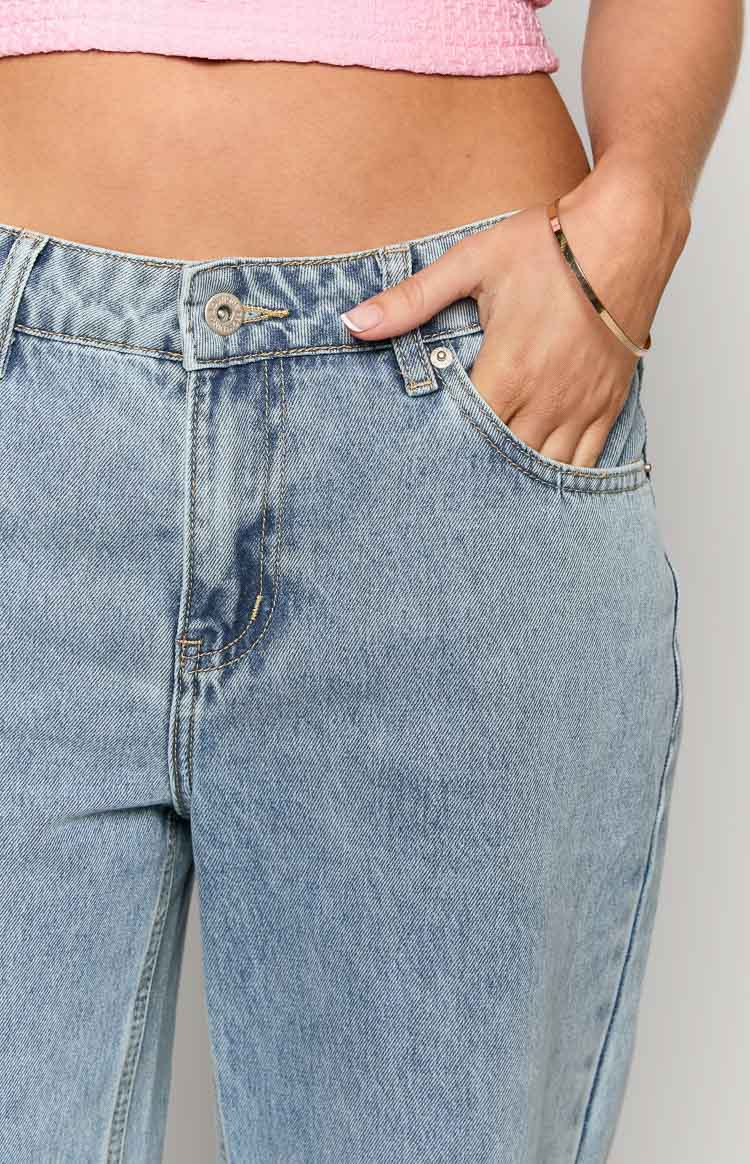 Close-up of the low rise mid wash denim jeans showing the button closure and front pockets