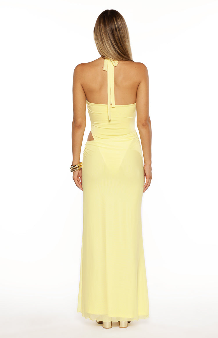 Rear view of a yellow halter neck maxi dress with side waist cutouts, low back, and sheer maxi skirt