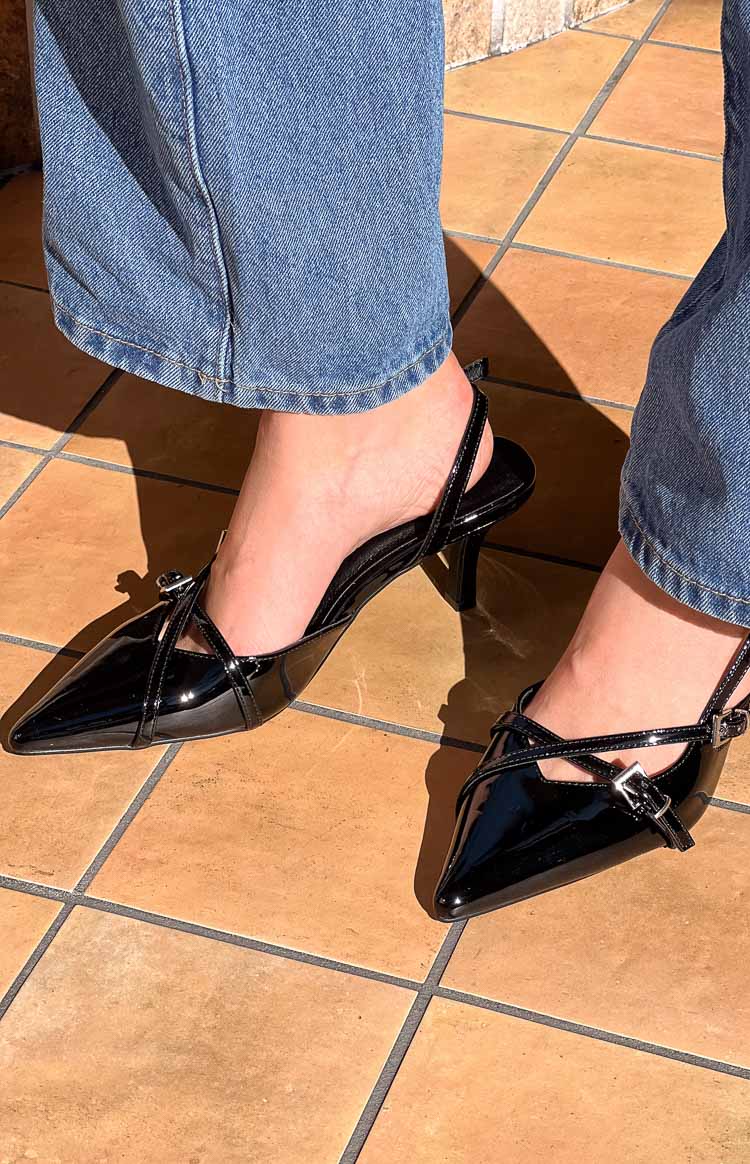 Black patent slingback heels with pointed toes, criss-cross buckled straps, and a kitten heel