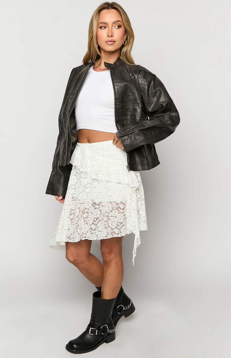 Side view of a white tiered lace mini skirt with an asymmetrical hem and floral pattern