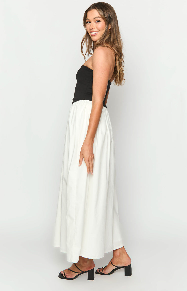 Side view of a black strapless top and a white flowy maxi skirt with a gathered waist on a contrast maxi dress