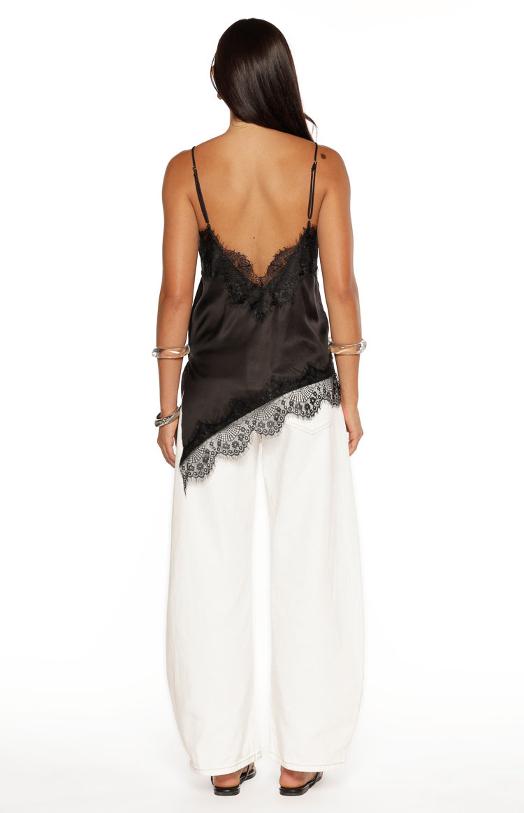 Rear view of a black satin asymmetrical top with a low lace-trimmed scoop back and an asymmetrical lace hem