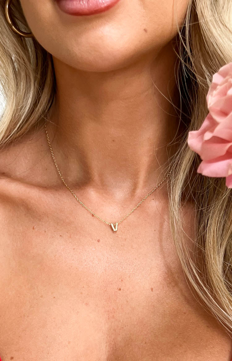 Close-up of the gold letter V pendant on a delicate gold chain necklace