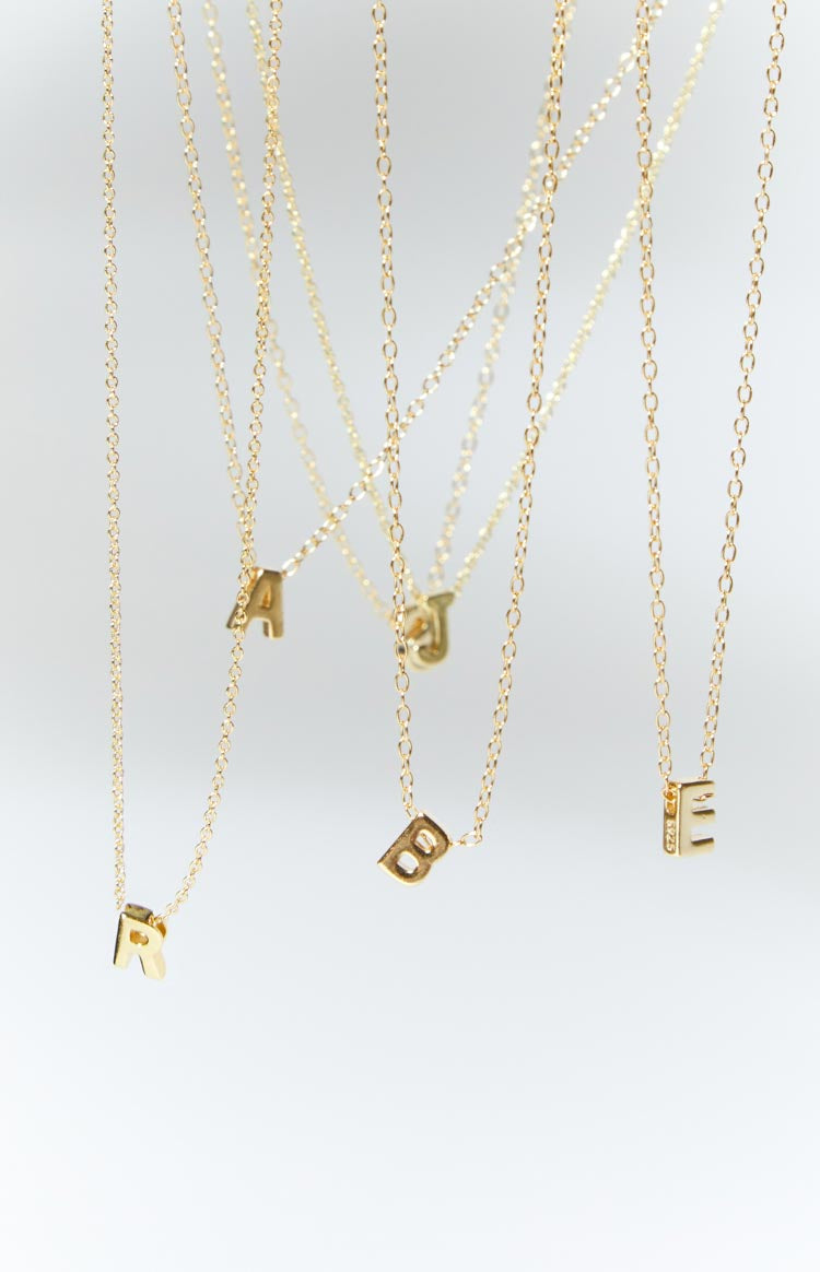 Multiple gold chain necklaces with block letter pendants R, A, J, B, E hanging at different heights