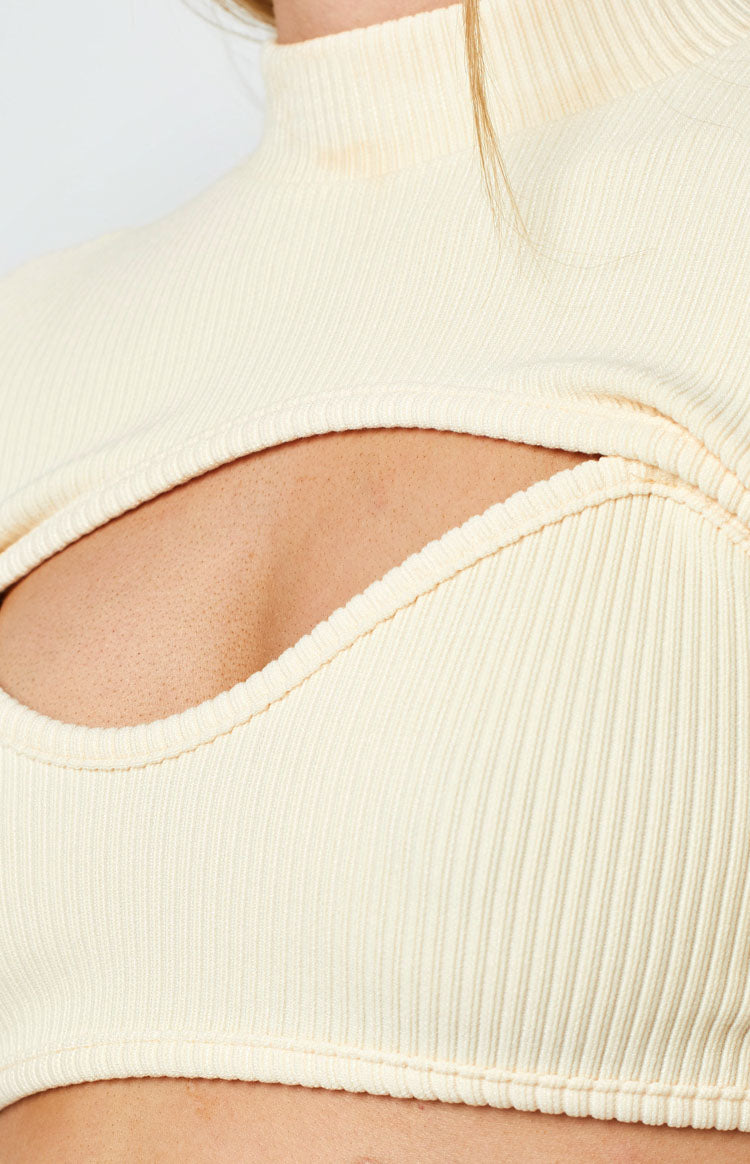Cream ribbed knit top featuring a high neck and a large oval cutout detail on the chest