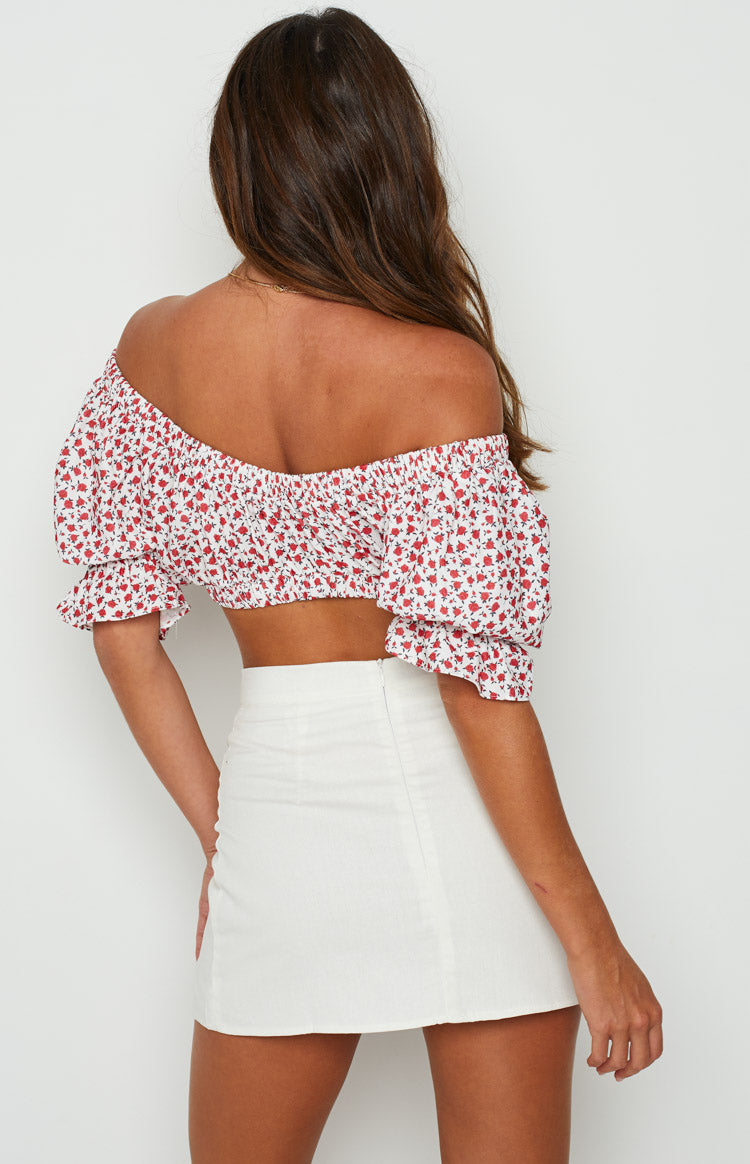 Rear view showing the smocked back and off-shoulder neckline of a white crop top with red floral print