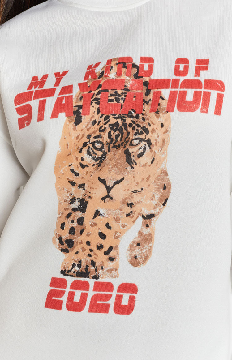 White dress with a graphic print of a stalking leopard and bold red text 'MY KIND OF STAYCATION 2020'