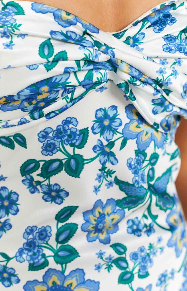Close-up of the twisted sweetheart neckline and blue and green floral pattern on a white maxi dress