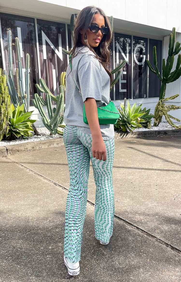 Rear-side view of green mesh mid-rise pants with a white and green wavy dot pattern and flared leg