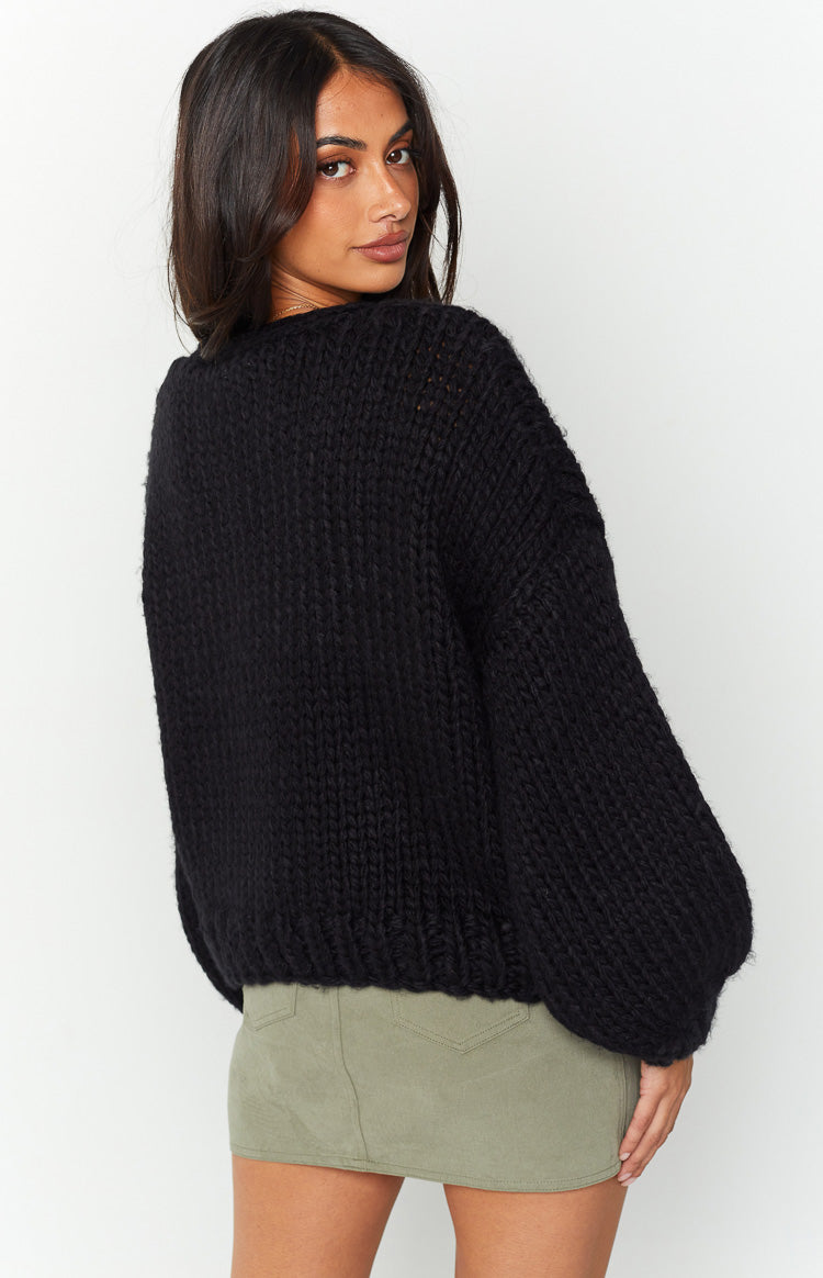 Rear view of a black chunky knit cardigan with dropped shoulders and balloon sleeves and ribbed hem
