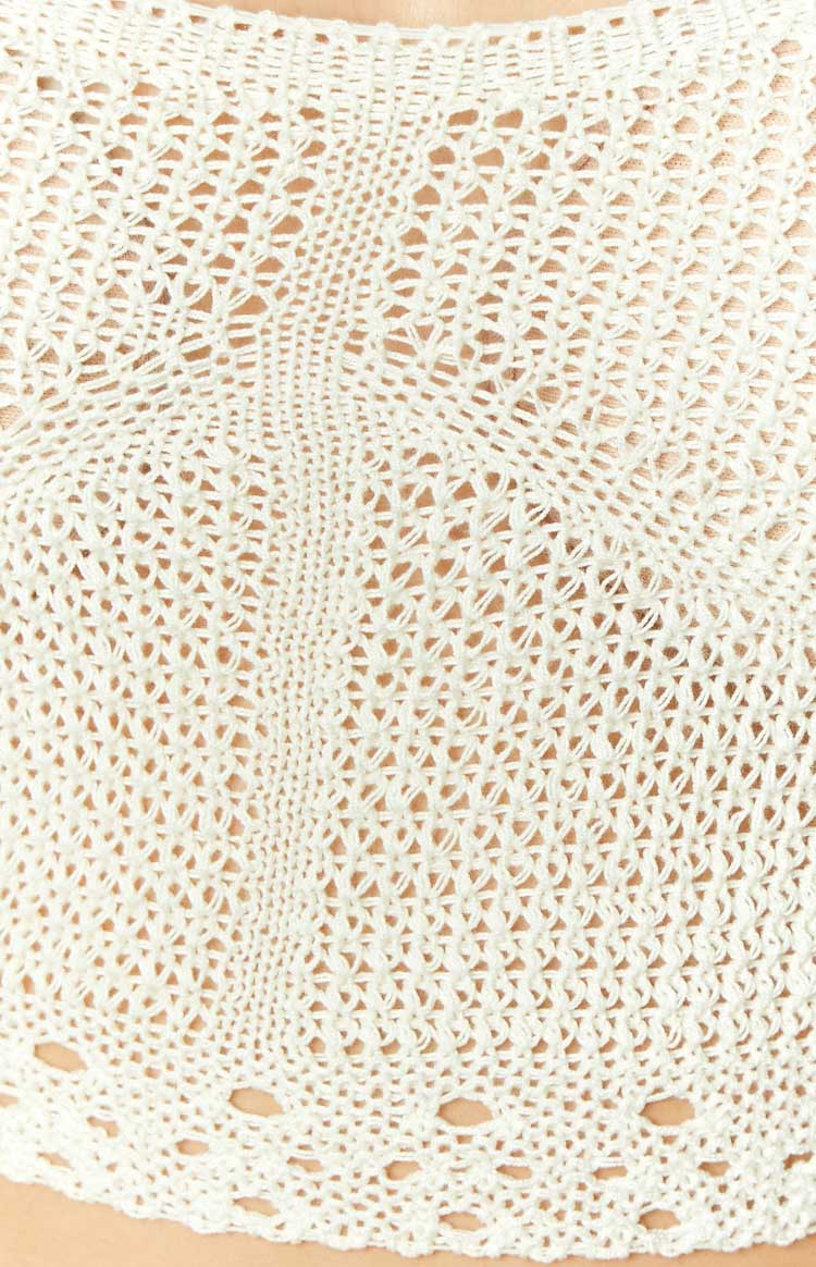 Close-up of the cream crochet knit top showing the intricate open weave pattern and scalloped hem