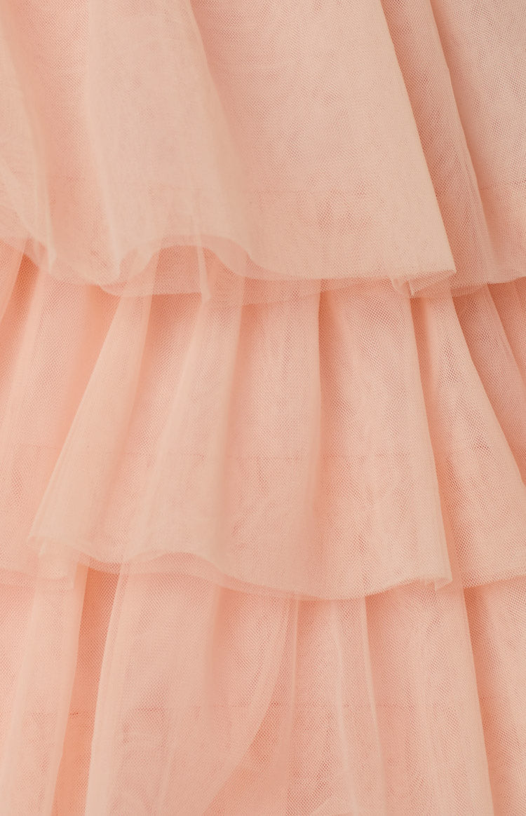Close-up of the soft pink tiered tulle ruffles creating volume on the mini dress