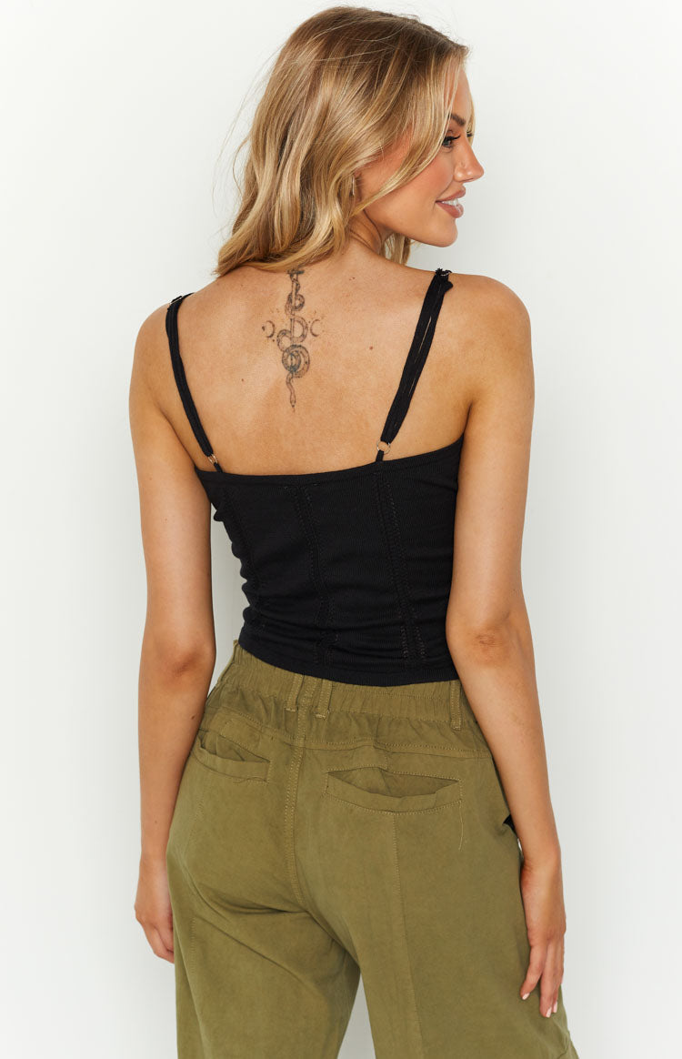 Rear view of a black ribbed knit crop top with thin adjustable spaghetti straps and vertical seam details